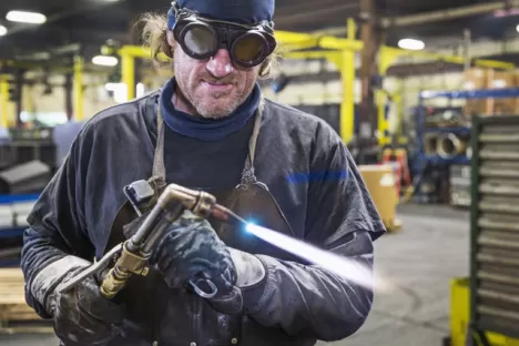 Soudeur réglant un chalumeau dans une usine