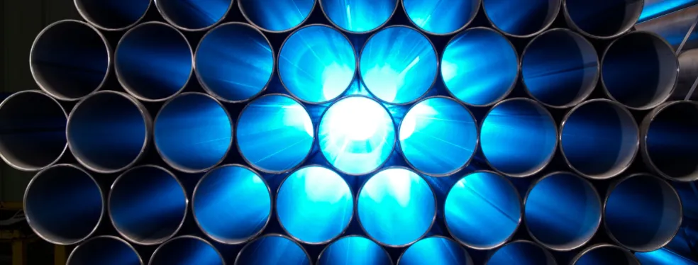 Empilement de tubes en acier industriels avec un rétroéclairage bleu.