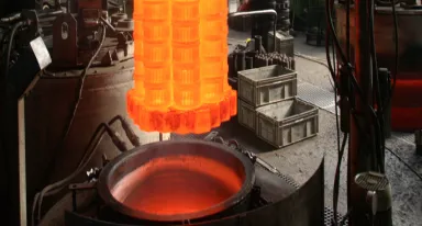 Pièces métalliques incandescentes chargées dans un four de traitement thermique industriel.