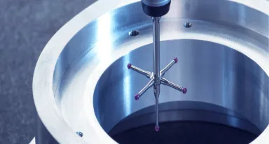 Palpeur de mesure tridimensionnelle inspectant une pièce en acier usinée.