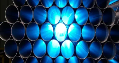 Empilement de tubes en acier industriels avec un rétroéclairage bleu.